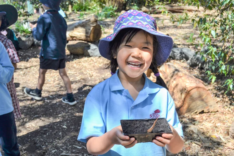 A smiling student holding a seedling punnet