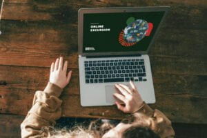 Child sitting at a laptop watching an CERES online excursion at a wooden table