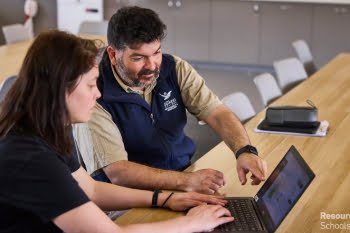 Two teachers look at a computer together