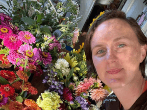 Meg Sheehan poses with cut flowers from the market garden she tends with another PDC grad Clare.