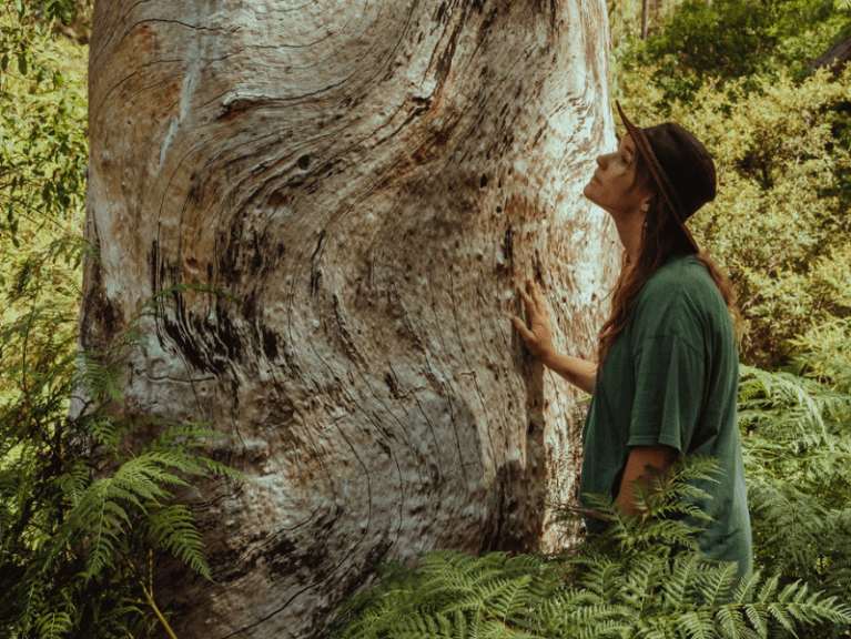 A person on CERES Nature Based Leadership Training course stands in front of a large ancient tree.