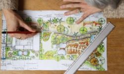 Person draws on their site map for permaculture design plans for a garden